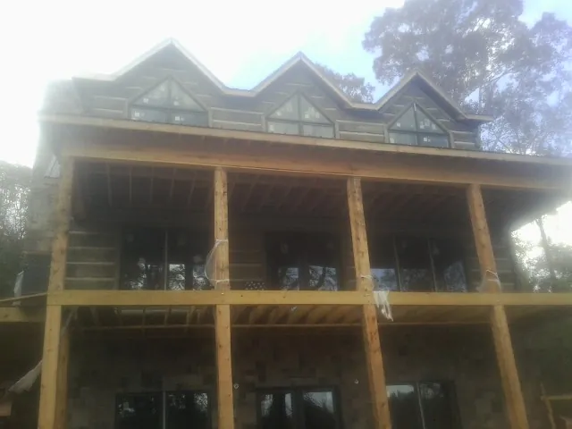 Dormers and porch framing on a large log home under construction — Roof Coating work by our crew in Eastman