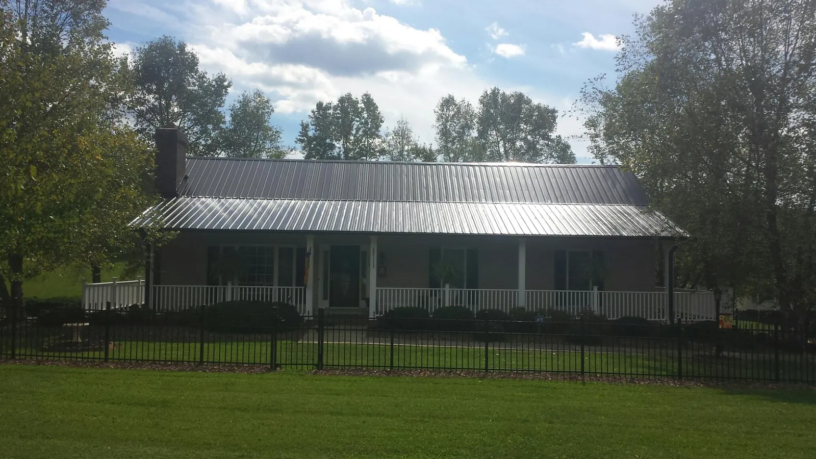 Gray metal roof on a brick ranch with a full width front porch — Gutter Guard Installation work by our crew in Eastman