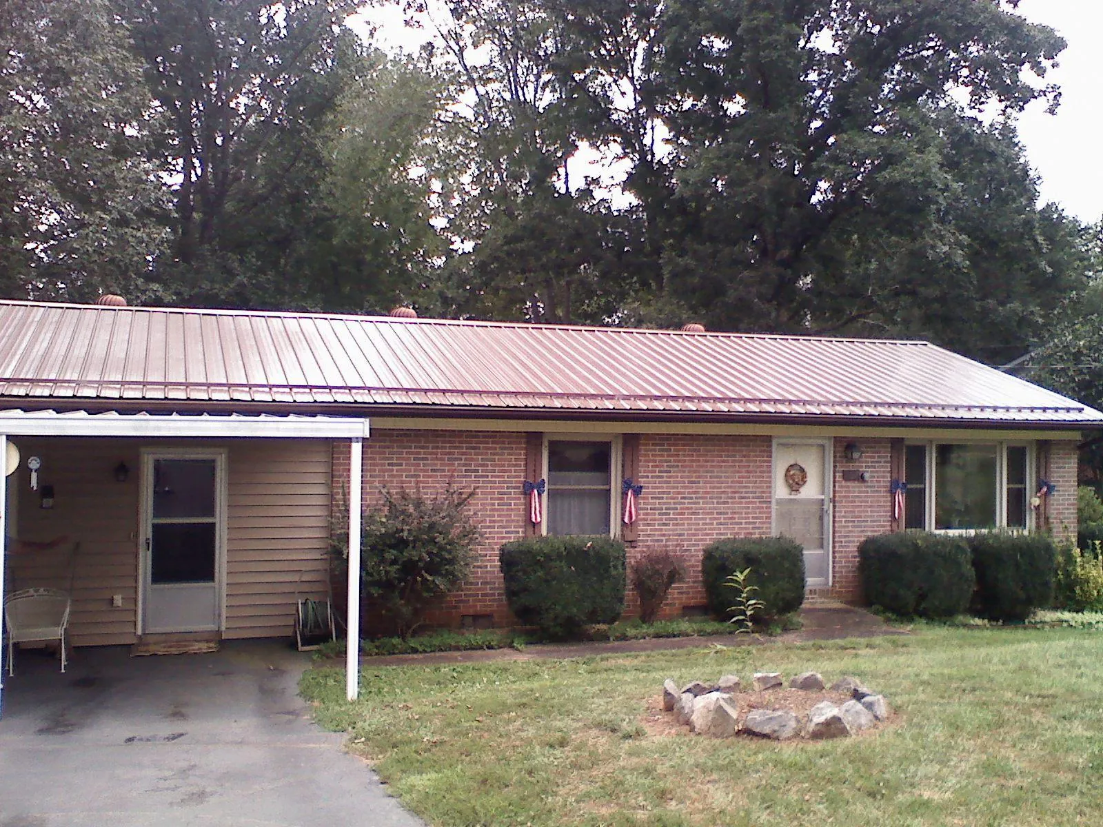 Bronze metal roof and carport on a brick ranch home — Roof Repair work by our crew in Eastman