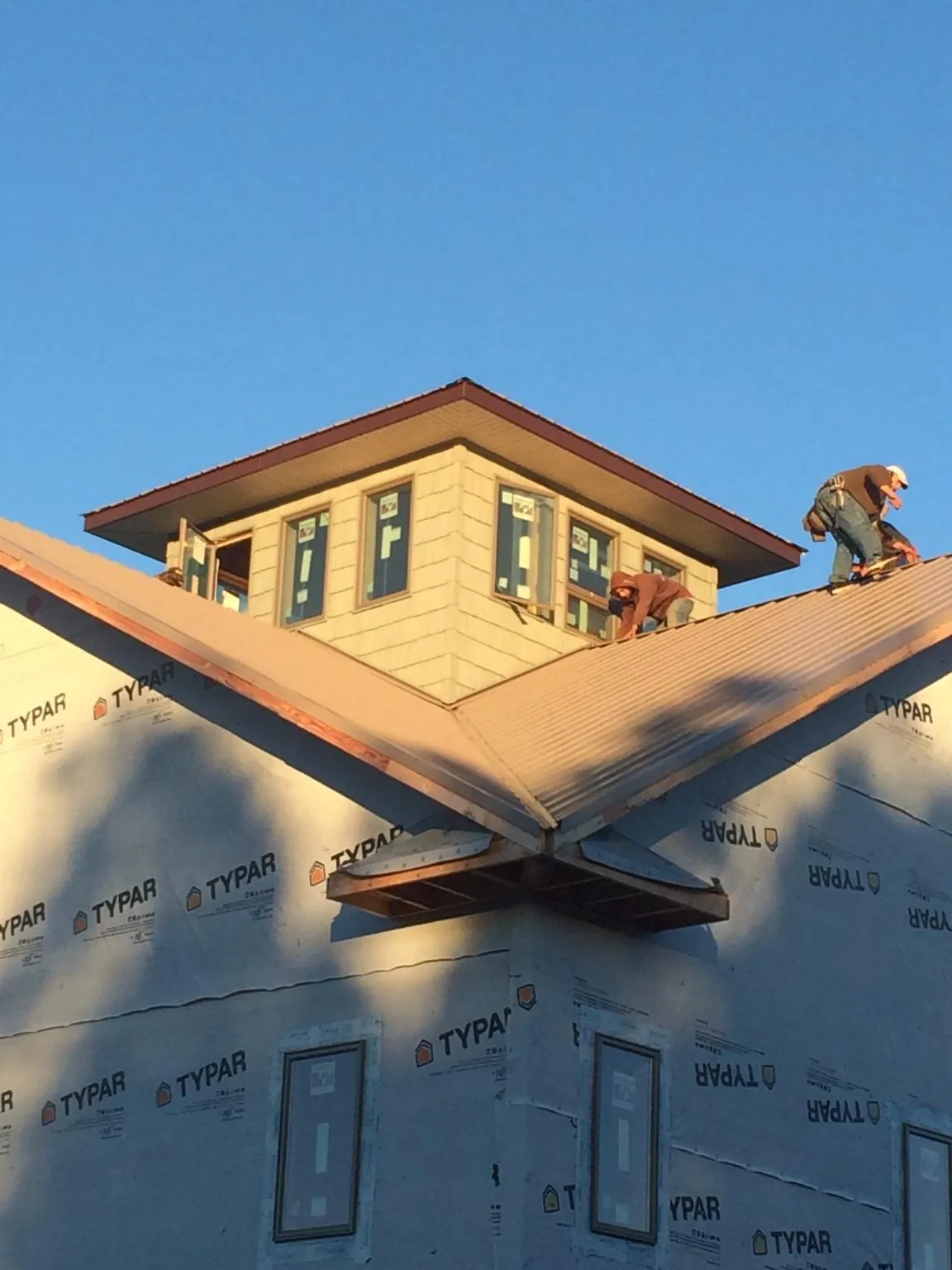 Roofers working around a rooftop cupola on a new metal roof at sunset — Roof Waterproofing in Eastman by Roofing Brothers